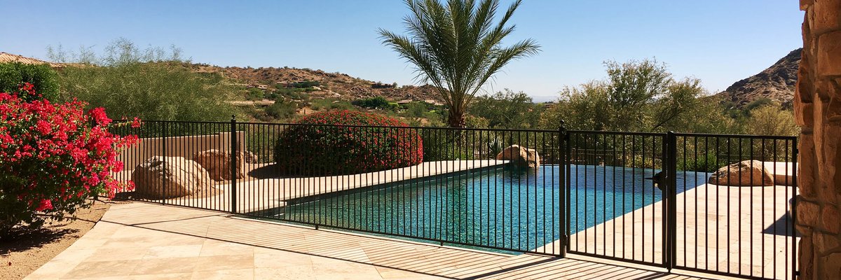 A black metal pool fence and gate around a backyard pool in Queen Creek, AZ.